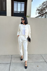 a lady in a white top, a white jacket and a pair of white pants